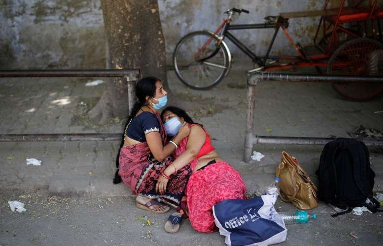 Women mourn the death of a family member who died from the coronavirus disease 1