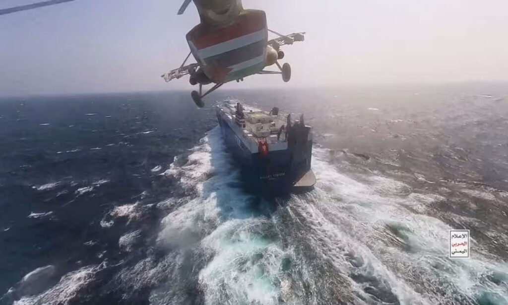 A Houthi helicopter flies over a cargo ship in the Red Sea